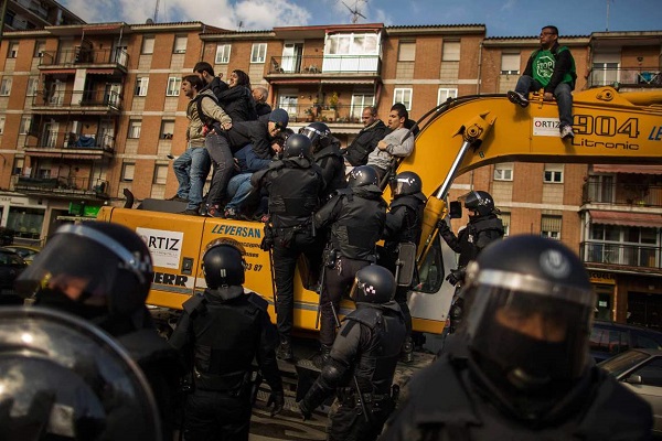 Riot Police remove a housing rights activists who claimed a bulldozer as they triy to stop Luisa Gracia Gonzalez and her family's eviction and the demolition of their house by a forced expropriation in Madrid, Spain, Friday, Feb. 27, 2015. Madrid authorities say 11 people were arrested after several dozen protesters clashed with police who were carrying out an eviction order.A city spokeswoman said seven people were arrested for throwing gasoline at police officers, though she said the fuel was not set alight. The official spoke on condition of anonymity in keeping with city hall rules.Evictions in Spain have soared since the country's economic crisis began in 2008 and increasing numbers of people were unable to meet mortgage payments. Protesters regularly try to prevent evictions, but Friday's clash was particularly tense after a campaign to keep the family in its home. The house was expropriated for demolition as part of new urban project. Some 30 protesters tried to stop it, accusing authorities of real estate speculation. (AP Photo/Andres Kudacki)